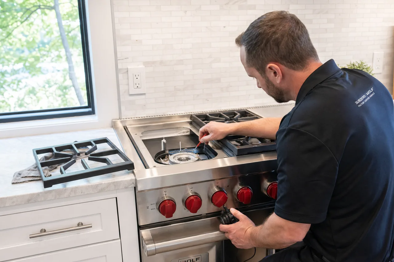 Technician servicing a stainless Wolf range mid-repair